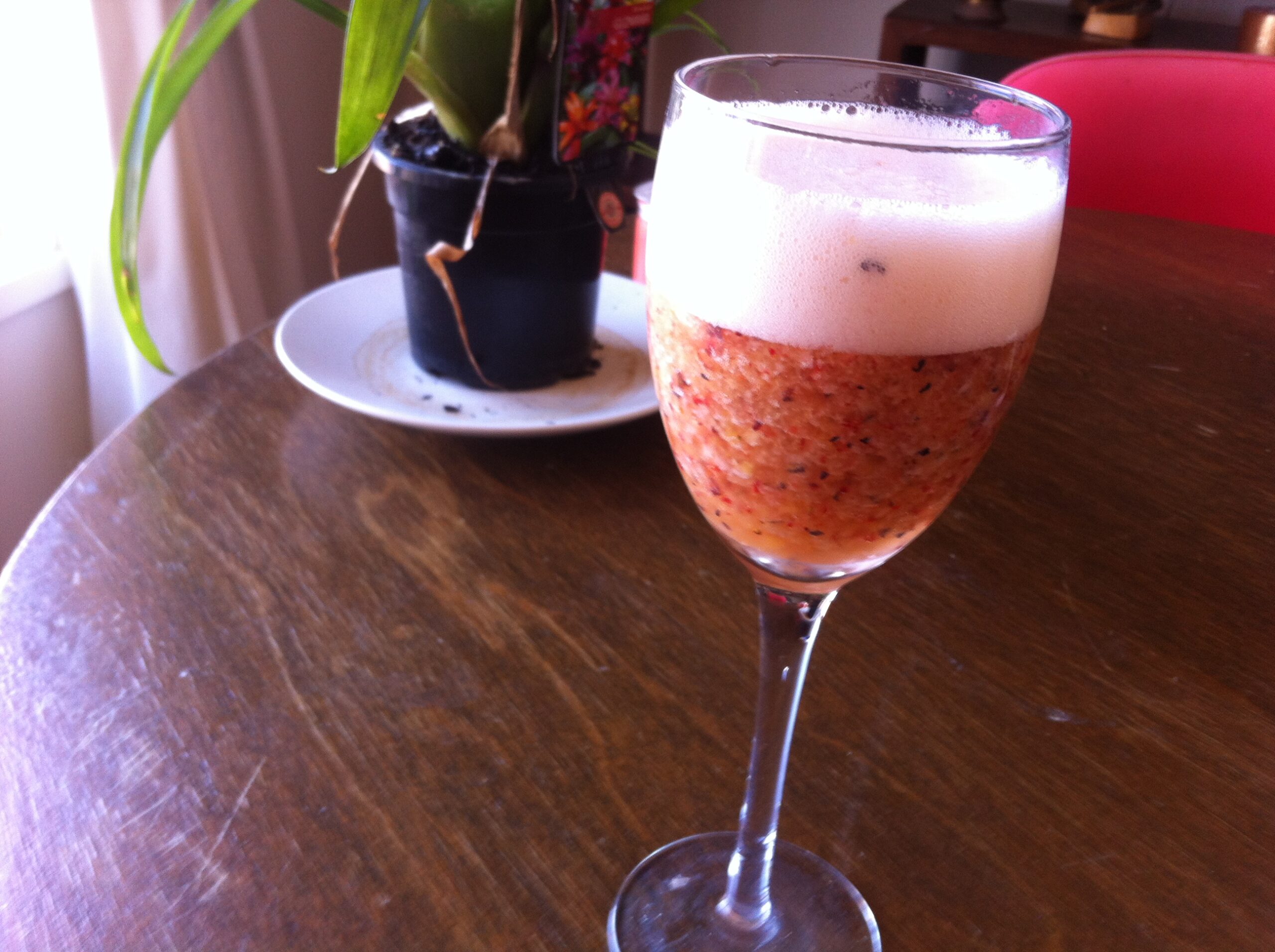 wine glass with cocktail in can see fruit with plant in background