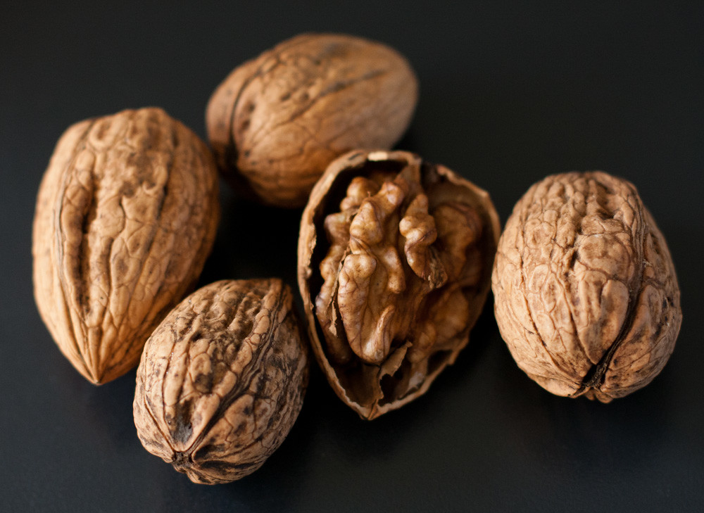 cracked walnuts, showing the nut in a shell - many people ask why do walnuts look like brains. An understanding of walnuts and brain health and the history of walnuts helps to answer this question