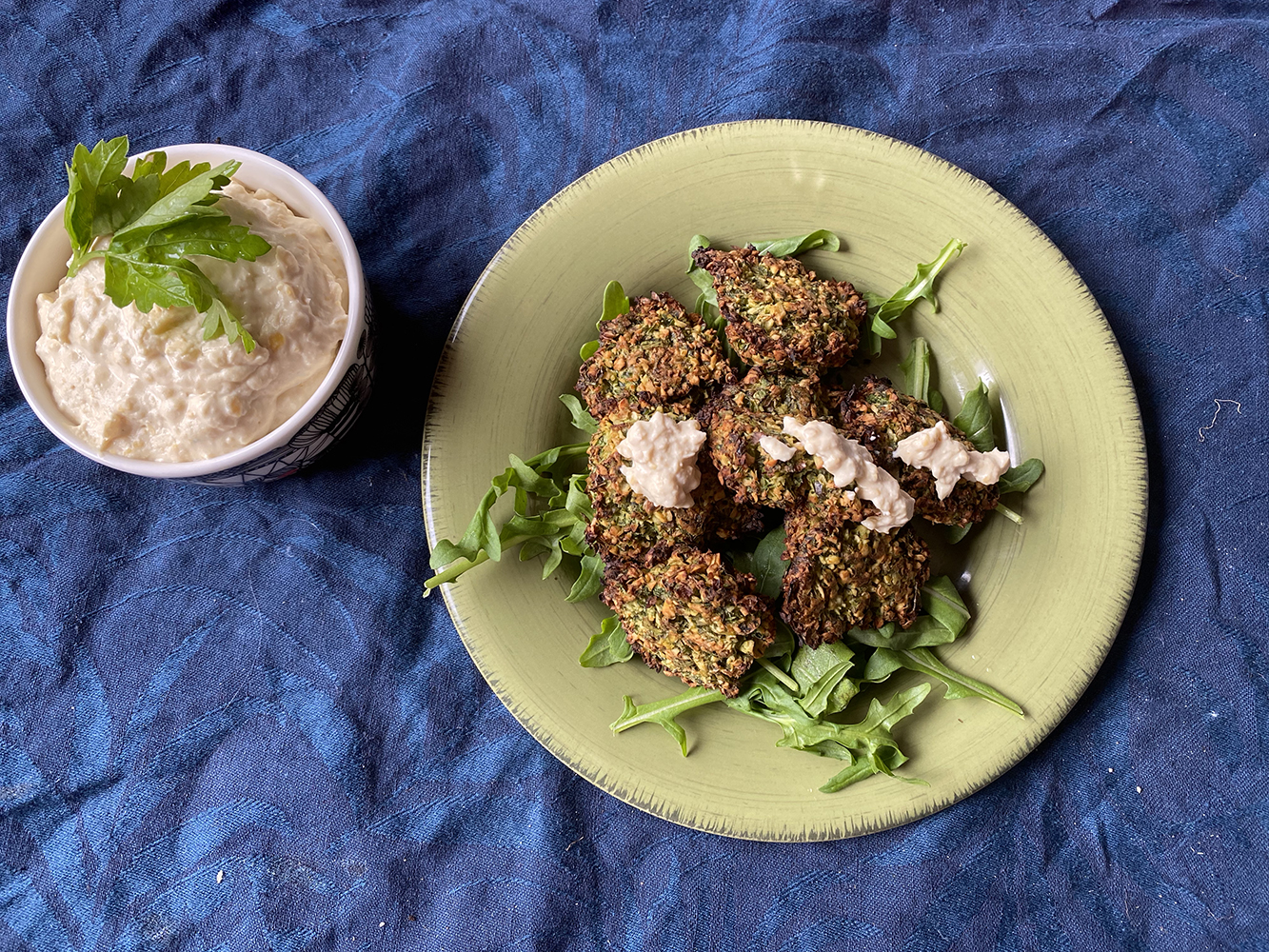 is falafel healthy? - vegan baked falafel on plate with leaves and near hummus dipping sauce