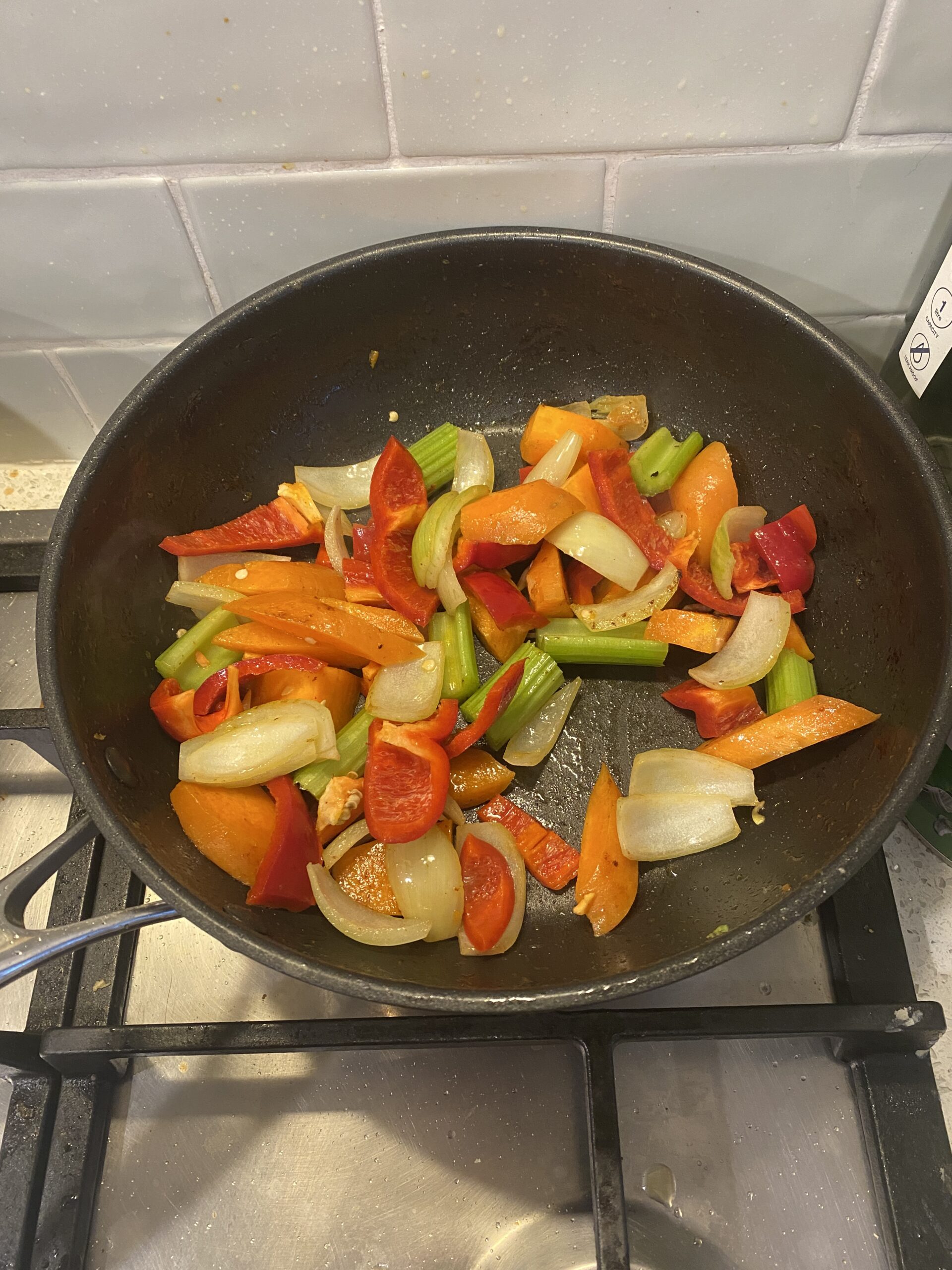 colourful vegetables in a stir fry on a cooktop - onion, carrot, capsicum, celery and others