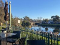 view to river and bridge and trees in the distance on a sunny afternoon - looking across cafe tables