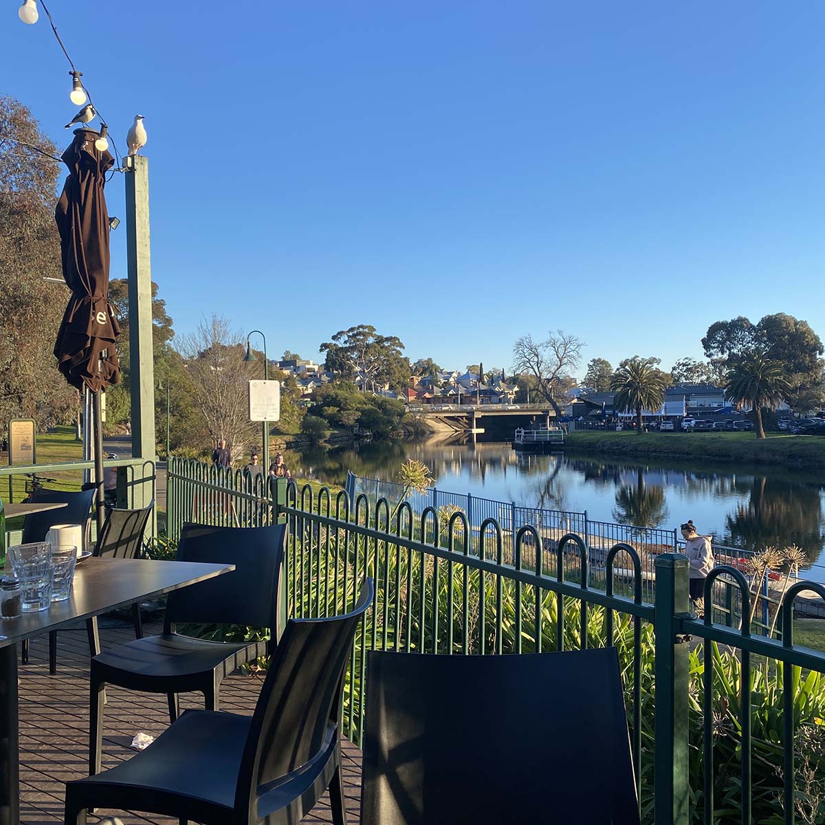 view to river and bridge and trees in the distance on a sunny afternoon - looking across cafe tables