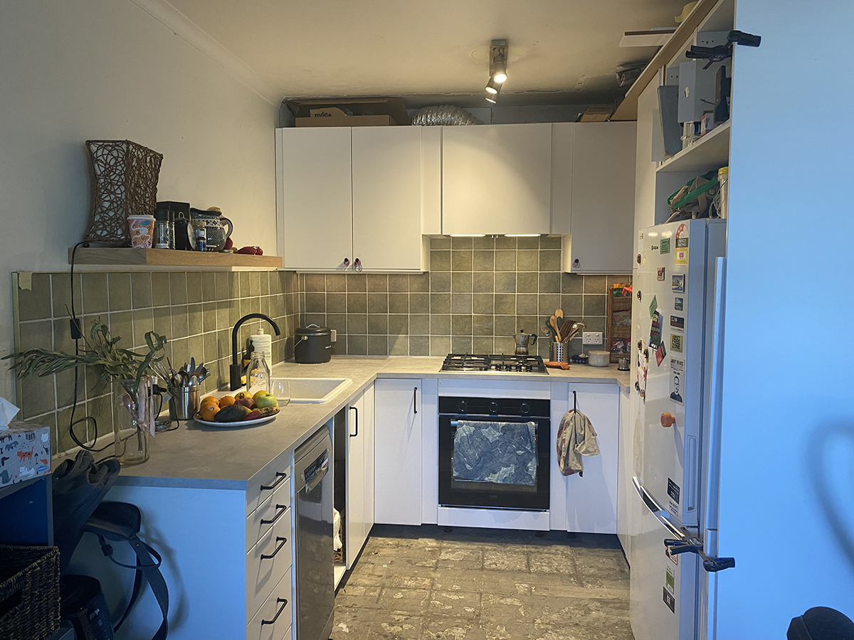 kitchen with green tiles, white cabinetry and concrete floor