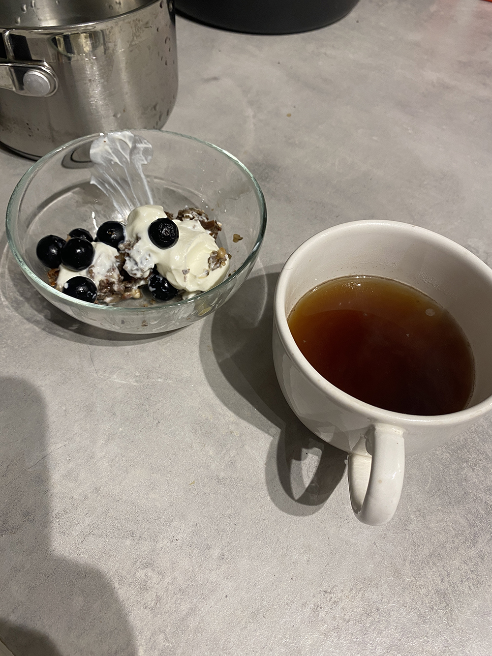 bowl with smear of yoghurt, nut bread and banana crumble and cup of coffee