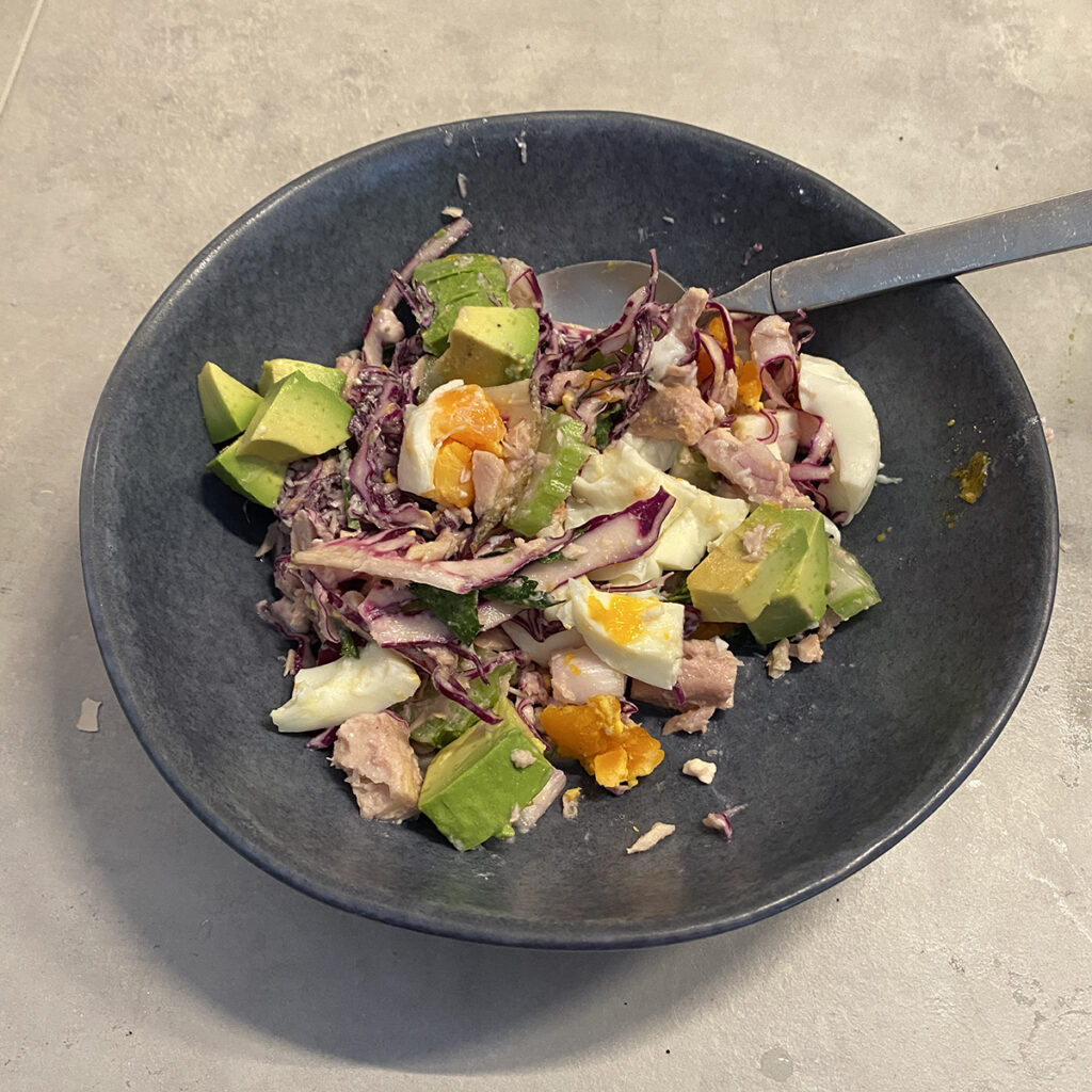 bowl of salad with purple cabbage, avocado and chopped boiled egg visible