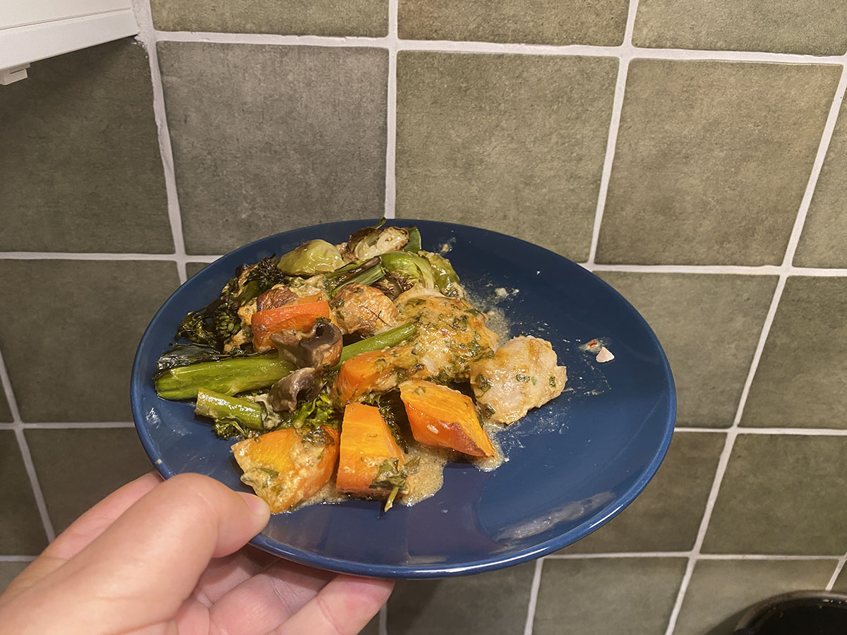 veggies and baked chicken on a blue plate in front of olive green tiles