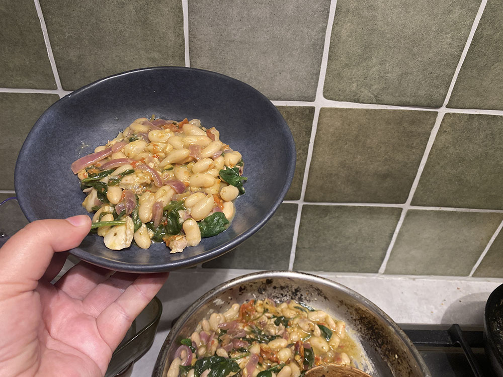 bowl of pesto beans above frypan with pesto beans