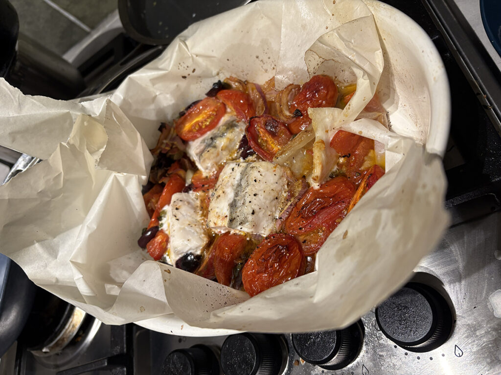 white baking paper with tomatoes, capers, fish, olives and onions