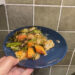 veggies and baked chicken on a blue plate in front of olive green tiles
